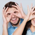 Smiling people making glasses shapes with their hands