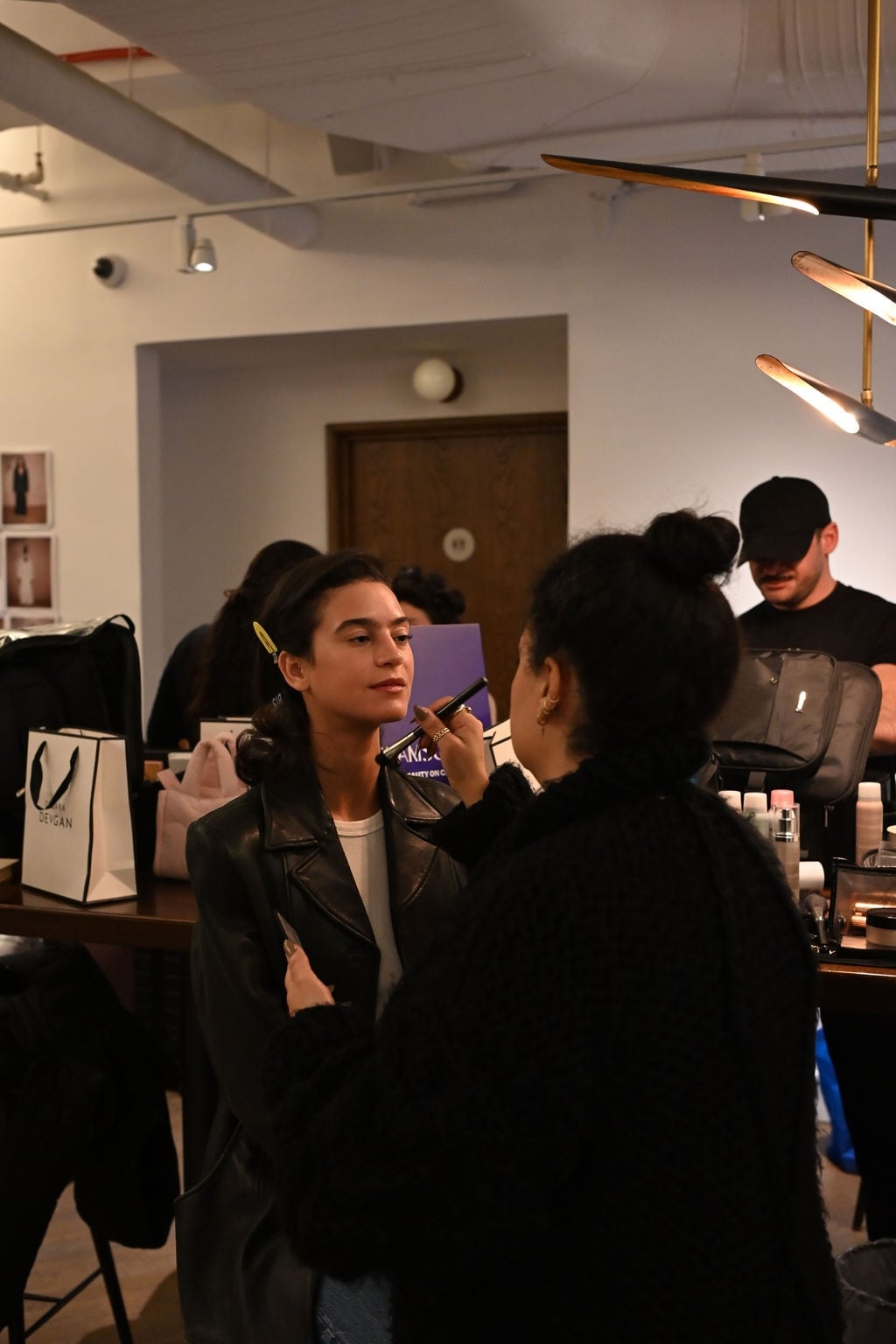 A makeup artist applying makeup to a client backstage at an event