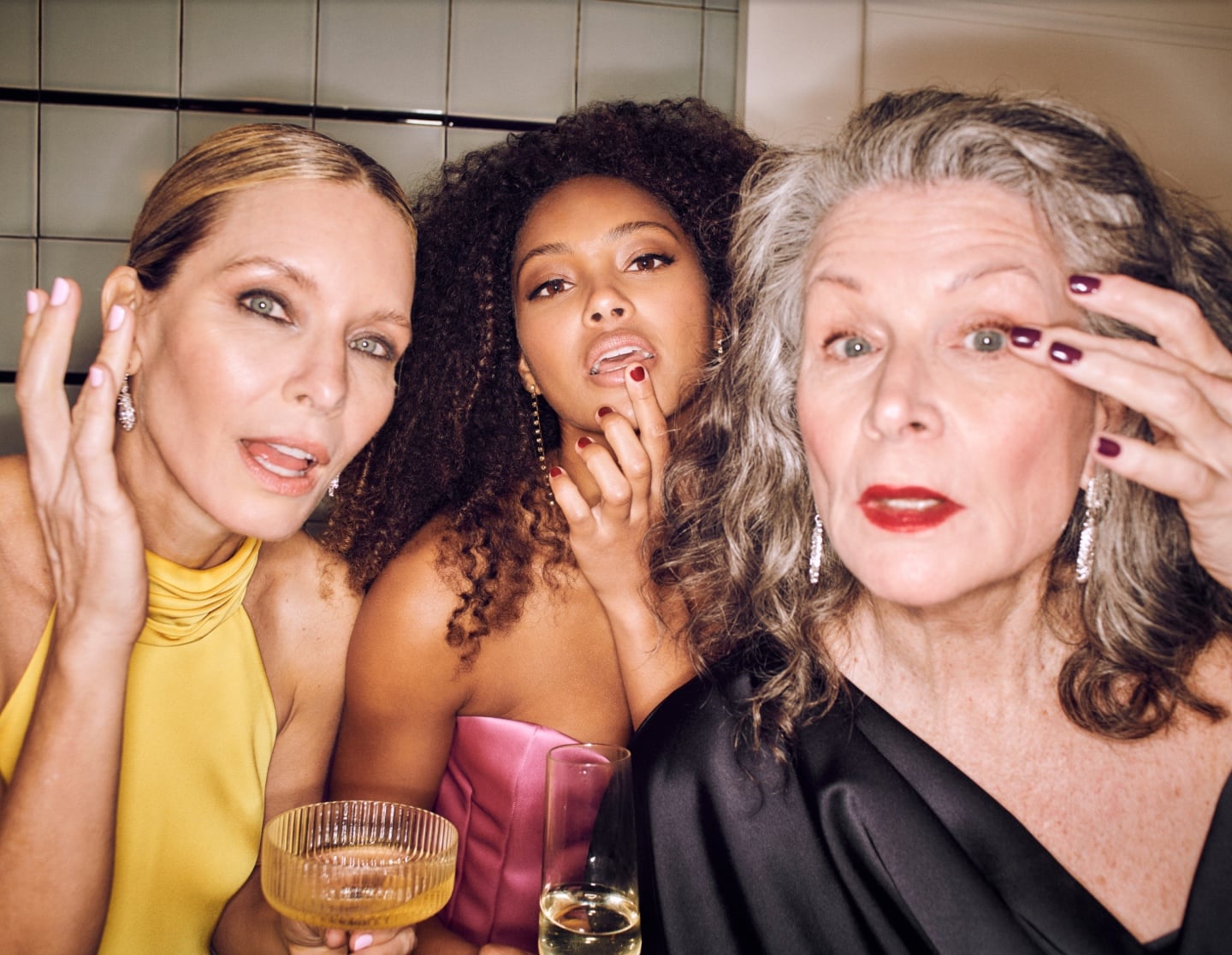 Friends with styled hair and makeup posing together during an at-home group glam session