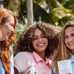 Three women holding Happy V wellness products outdoors