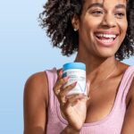 Woman holding Happy V Prebiotic + Probiotic against a blue background