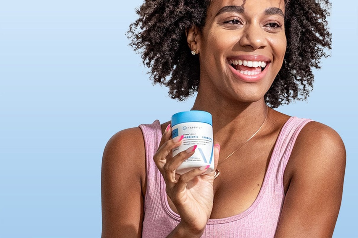 Woman holding Happy V Prebiotic + Probiotic against a blue background