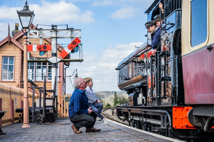 A child and grandfather speak with railway conductors