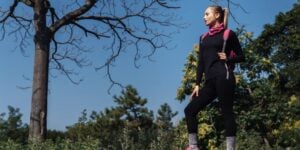 Hiker wearing black merino layers and a backpack on a wooded trail