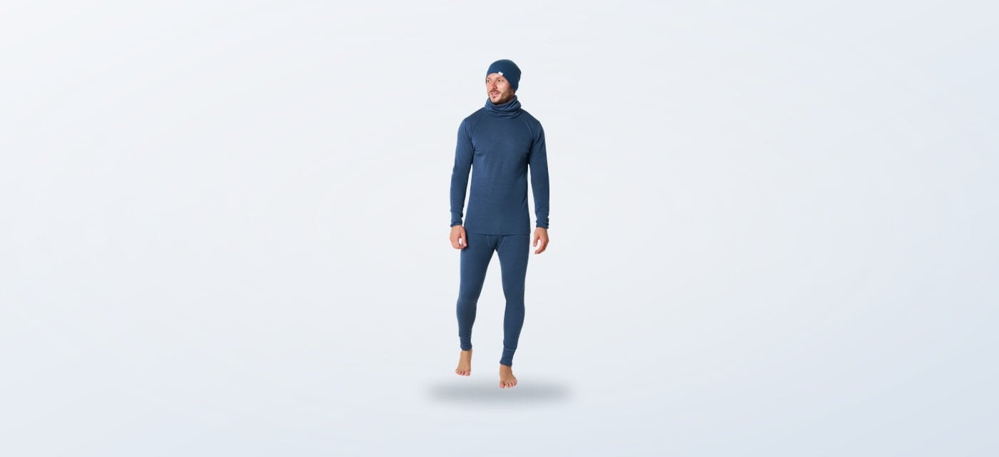 Man wearing a denim blue merino base layer with matching beanie and neck gaiter