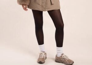 Model wearing a mocha longline puffer jacket with a faux fur trimmed hood