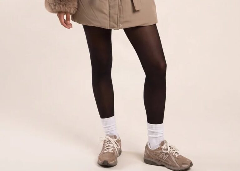 Model wearing a mocha longline puffer jacket with a faux fur trimmed hood