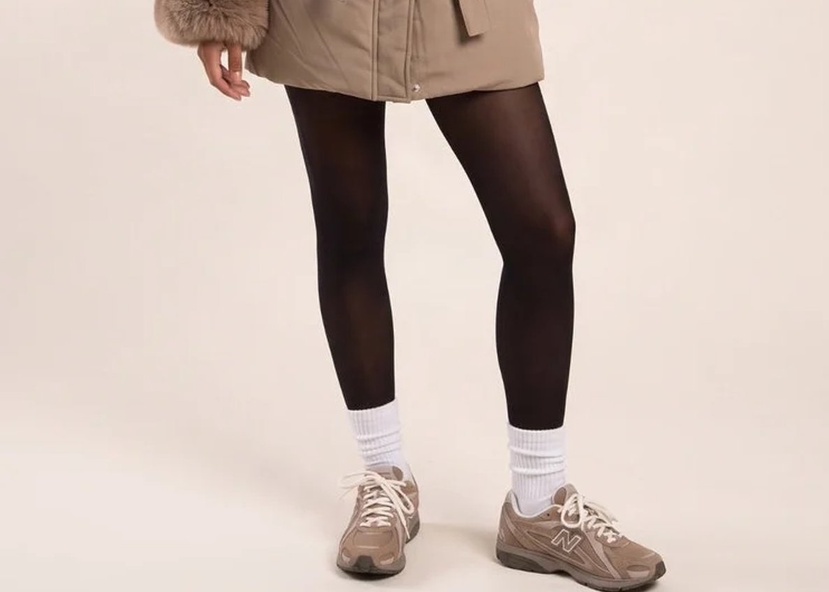 Model wearing a mocha longline puffer jacket with a faux fur trimmed hood