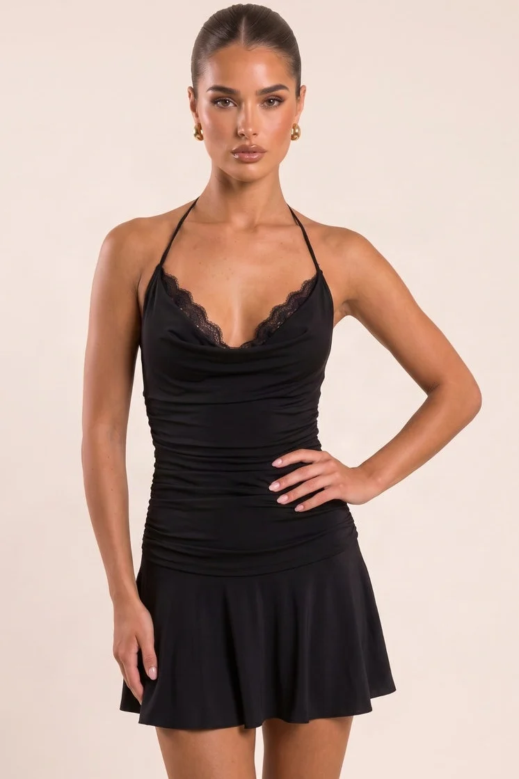 Model wearing a black mini dress with cowl halterneck and lace panel