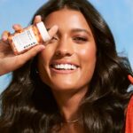 Model holding a REHAB Your Hair capsule bottle
