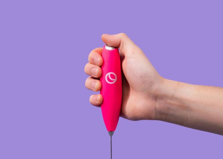 A hand uses the pink Spacegoods frother to mix a drink