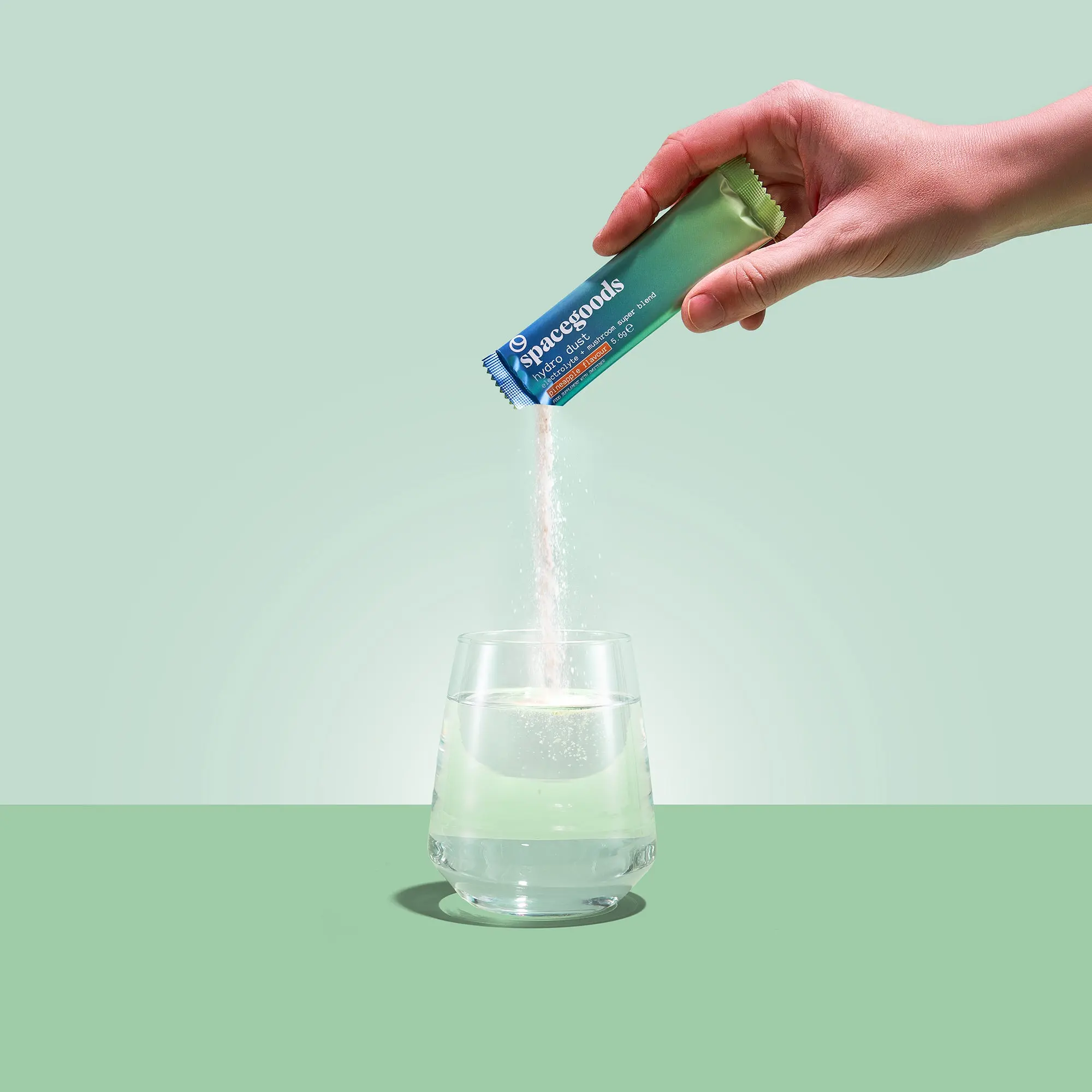 Pineapple Hydro Dust sachet being poured into a drink