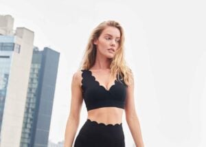 Model wearing black 7/8 high-waist leggings with scalloped trim